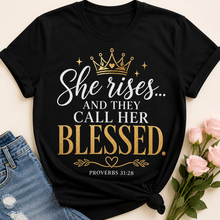 Load image into Gallery viewer, Black T-shirt with She rises and they call her blessed Proverbs 31:28 design in gold and white