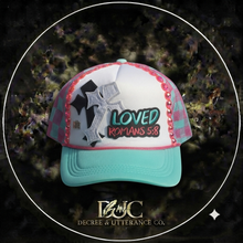 Load image into Gallery viewer, Turquoise and pink trucker hat with Loved, cross, and Romans 5:8 design
