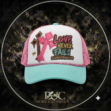 Load image into Gallery viewer, Turquoise and pink trucker hat with Love Never Fails, cross, and 1 Corinthians 13:8 design
